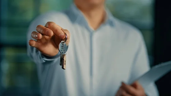 Estate agent salesman banker businessman show at camera bunch of keys from new house commercial offer housing mortgage successful homeowner buyer rent accommodation in business centre office building