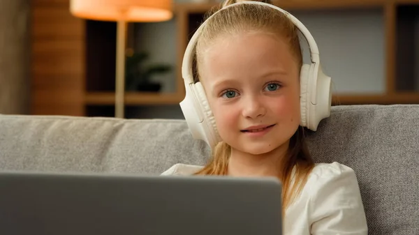素敵な幸せな子供かわいい女の子でヘッドフォンで座っているアパートで音楽を聴くラップトップ演奏コンピュータゲーム面白い小さな子供の女の子幼児の腕時計ビデオ勉強オンラインホーム教育Eラーニング — ストック写真