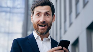 Yakın plan şaşkın adam cep telefonundan e-posta bildirimi okuyor mutlu haberler alıyor duygusal iş adamı online bahsi kazanıyor kumarhane kârlı bir iş teklifi alıyor