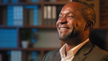 Yakından bakınca komik kaygısız iş adamı gülümseyerek eğleniyor içten duygular hissediyor neşeli Afrikalı Amerikalı bir adam esprili bir şakayla gülüyor komik bir durum.