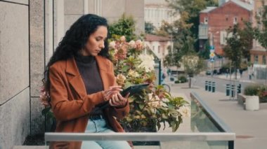 Ciddi bir şekilde düşünceli iş kadını Kafkasyalı kadın Latin bayan yönetici CEO dijital tablet kablosuz cihaz altlığı ile balkon ofis terasında web taraması yapıyor.