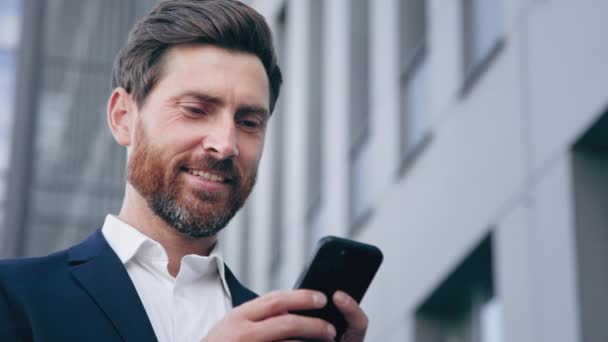 特写镜头优雅英俊的大胡子男人拿着手机发邮件在网上交流成功的商人计划利用智能手机与商业伙伴聊天的移动应用程序组织日程安排 — 图库视频影像