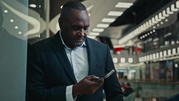 非洲裔美国成年人中年男性商人创业者聊天浏览滚动手机屏幕移动应用网络电话智能手机办公室购物中心的Wi — 图库视频影像