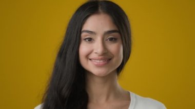 Sarı stüdyo arkaplanlı yakın plan portre 20 'li yaşlarda Hintli etnik kadın kız arkadaş kız model müşteri gülümseme yüz ifadesi kozmetoloji dermatolojisi makyajı