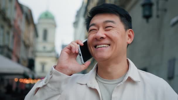 快乐的男人站在户外用手机聊天 笑着成年男性游客接听友好的电话命令出租车用智能手机与朋友在手机上交流距离有趣的远距离交谈 — 图库视频影像