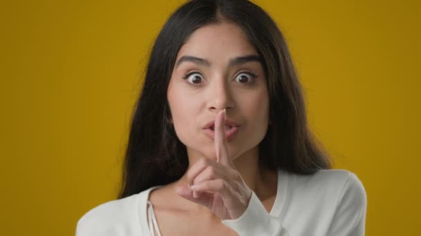 スタジオで女性の肖像黄色の背景インドの20代の女性民族の女の子の女性は ハッシュジェスチャー沈黙サインを示す停止禁止仕上げゴシップミステリープライバシー秘密情報秘密話 — ストック動画