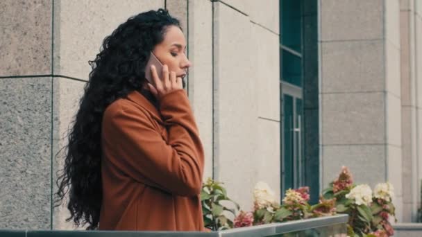 严肃的白种人西班牙裔少女女商人女商人走到自家写字楼的阳台上 与人谈论手机 进行遥远的虚拟交谈 接电话 讲智能手机 — 图库视频影像