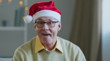 Kapalı portre. 60 'ların beyaz, yaşlı, olgun, Noel Baba şapkalı, evde şarkı söyleyen, dans eden, dans eden, Noel partisinde eğlenen adam.