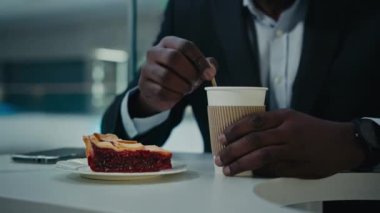 Tanınmayan Afrikalı, resmi takım elbiseli, kafeterya restoranında masada oturan, şekerli, aromatik kahve, latte cappuccino içen, vişneli pasta yiyen, tanınmamış bir iş adamı.