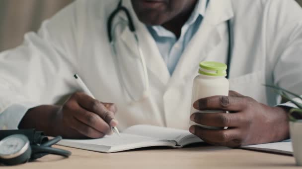 未知のアフリカ人医師セラピスト心臓病の薬剤師は 病院の診療所に座る書き込み診断医療レシピ健康予約通知薬の投与量免疫のためのビタミン錠 — ストック動画