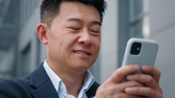 市内の男性を閉じます屋外の電話画面アジアの40代のビジネスマン起業家スマートフォンのチャットブラウジングでモバイルアプリマップナビゲーションを使用して雇用者の男性遠隔仮想主催者 — ストック動画