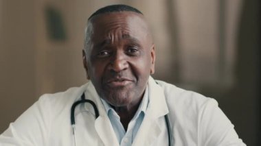 Kameraya bakan Afrikalı Amerikalı erkek doktor pratisyen terapist görüntülü sohbetten uzak konsültasyon hastasını arıyor. Sanal tıbbi danışmanlık sağlık hizmetleri sunuyor.