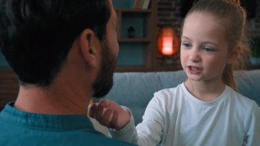 Sevecen küçük kız çocuğu babasıyla oynuyor. Yüzüne dokunuyor. Yumuşak erkek sakalını okşuyor.
