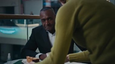 Tanınmayan garson, orta yaşlı Afrikalı işadamı pastası ve çay kahveli latte kapuçino getiriyor. Erkek kapuçino içiyor. Kafeteryada öğle yemeği molası için otururken tatmin oluyor.
