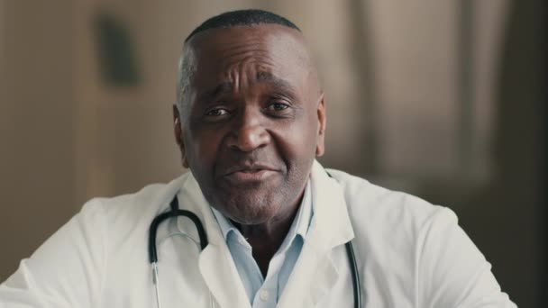 アフリカ系アメリカ人男性医師のセラピスト心理学者は ビデオチャットで遠隔相談患者を呼び出すカメラを見て仮想医療相談遠隔医療サービスを提供します — ストック動画