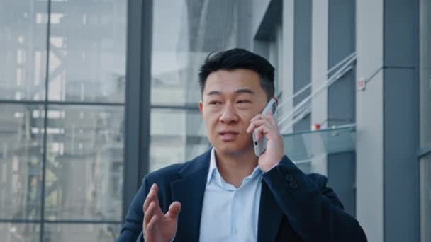 閉じるアジア40代の中高年実業家の雇用主の男は 仮想主催者を呼び出すスマートフォンと同僚とモバイル会話の交渉を話して街のダウンタウンを歩いて — ストック動画