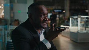Afrika kökenli Amerikalı son sınıf öğrencisi orta yaşlı bir adam hoparlörden ses tanıma mesajı kaydediyor. 50 'lerin etnik işadamı sanal telefon uygulaması kullanarak alışveriş merkezindeki akıllı telefondan hatırlatıcıyı ayarladı