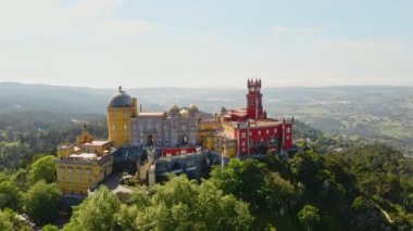 Portekiz 'in ünlü turistik yer mimari kompleksi Avrupa seyahati konseptinin Sintra panoramik kasabasının üzerindeki kayalık dağın tepesindeki Pena Sarayı' nın eski şatosunun insansız hava aracı görüntüleri.