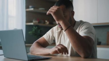 Afrikalı Latin erkek adam evde mutfakta online oyun oynuyor. Bahis kaybediyor. Kötü sonuç alınıyor.