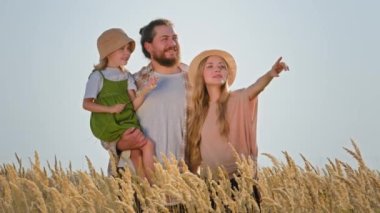 Kafkasyalı anne, baba, çocuk kız, kız çocuk, sakallı adam ve sarışın kadın, açık alanda buğday tarlasında.