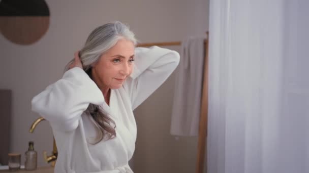 白种人老年老太太60多岁老太太洗澡时穿浴衣的奶奶模型摸着灰白色的长发光滑的稀疏头发担心脱发线的弱发老化问题脱发型老年病 — 图库视频影像