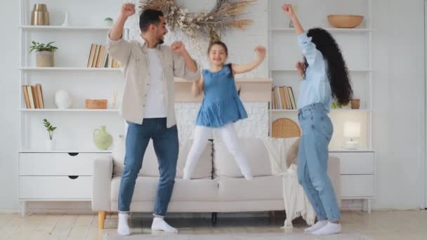 西班牙裔白人多民族多种族家庭在家里跳舞 妈妈爸爸的父母搬到音乐与女婴小孩跳沙发假装弹吉他滑稽舞 — 图库视频影像