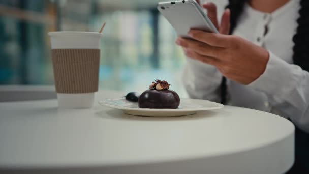 クローズアップ女子学生フードブロガーは ソーシャルメディアで写真を共有カフェでおいしいカップケーキとトレンディな朝食甘いチョコレートデザートとコーヒーを感じる喜びを撮影携帯電話を保持しています — ストック動画