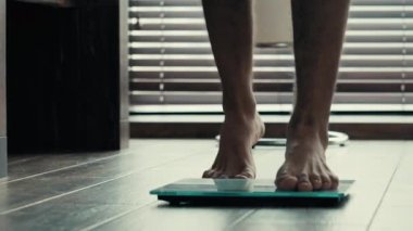 Yakın plan erkek bacakları elektronik terazinin üzerinde duruyor. Sportif tanınmayan erkek atlet yalın ayak vücut kilogramlarını kontrol ediyor spor eğitimi ve sağlıklı beslenme sonuçlarını kontrol ediyor.