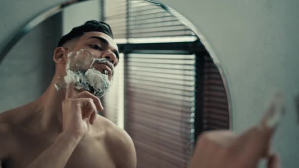 거울에 근육질의 인도인 남자의 남자가 면도를 준비를 얼굴에 거품을 내뿜고 — 비디오