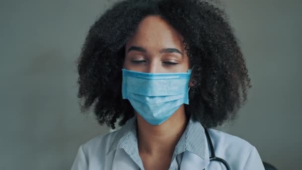 医療制服と保護マスクのプロの労働者アフリカの女性医師がCovid 19流行パンデミック発生時のビデオ通話コンサルティング患者オンライン無線通信医学会議に参加 — ストック動画