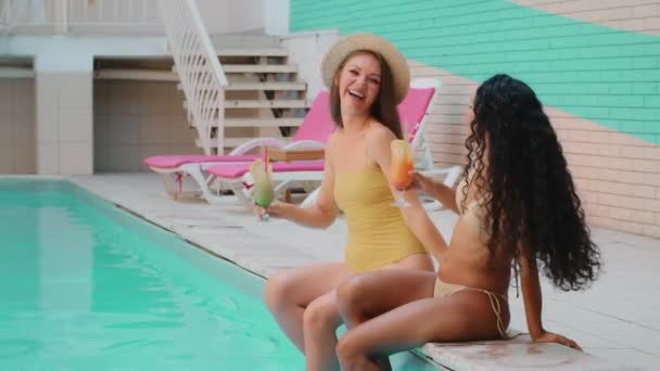 幸せな多民族アラビア語と白人の女の子の友人は 水プールで足をスイング若い女性の学生は一緒に季節の観光を楽しむリラックス夏のパーティーを祝う熱帯カクテルを飲む — ストック動画