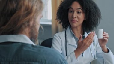 Afrikalı doktor, etnik kadın eczacı hasta erkek hastaya ilaç, kalp ilacı, kadın doktor, antibiyotik ilaç öneriyor.