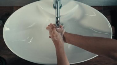 Yakın çekim erkek elleri banyoda yıkanırken evdeki otel odasındaki banyoda doktor kolları sterilize ediyor vücut bakımını temizliyor avuç içi temizliyor bakteri mikropları koronavirüs salgınını önlüyor.