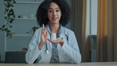 Çekici genç doktor kız öğrenci Afrikalı kadın eczacı profesyonel danışman ilaç şişesini sağlıklı vitaminlerle tutuyor. Eczane ilaçlarını destekleyen antibiyotik tabletleri alerji yapan kız.
