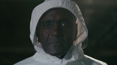 Özel korumalı beyaz kimyasal üniformalı doktor portresi salgınla savaşıyor. Üzücü bir ifadeyle kameraya bakıyor. Afro-Amerikan erkeği, pandemik olduğu için üzgün.