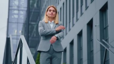 Başarılı bir iş kadını iş dünyasının arka planında duran ofis binasında kameraya bakıyor gururlu beyaz kadın profesyonel lider dışarıda kollarını kavuşturmuş poz veriyor.