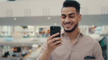 Hintli İspanyol işadamı girişimci alışveriş merkezi şirketinin ofisinde cep telefonuna bakıyor kahve içiyor iyi haberler okuyor, cep telefonu akıllı telefon uygulaması okuyor.