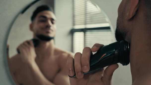 镜像倒影回顾英俊潇洒的拉美裔拉美裔男人胡须刮胡子刮胡刀刮胡刀在家里的浴室里刮胡子男性美容程序面对护理 — 图库视频影像