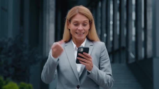 驚きの幸せなビジネスマンの女性は良いニュースでテキストメッセージを受信電子メールを読み取り興奮した喜びの女性の勝者は インターネット上で勝利の成功の喜びを祝う画面の携帯電話を見て — ストック動画