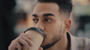 Yakın plan portre Hint etnik sakallı mutlu adam pozitif adam işçi girişimci iş adamı gülümsüyor kafe 'de kahve fincanından kahve içiyor ve içmekten keyif alıyor.