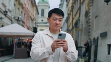 Gülümseyen Çinli erkek turist elinde telefonla sosyal ağda geziniyor. Yer belirleme adamı gezgini siparişi veriyor. İnternet 'te uzaktan kitap biletlerinde mobil uygulama kullanıyor.