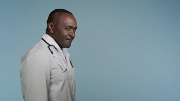 Африканский Американец Медицинском Халате Прогуливаясь Сером Фоне Студия Мужчина Врач — стоковое видео
