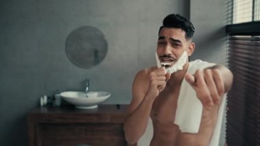 Neşeli, komik, esprili, Latin, sakallı, beyaz sabunlu, sakallı, köpüklü sakallı sakallı, sakallı adam tıraş olurken tıraş olurken tıraş olurken jiletle şarkı söyleyen, banyoda dans ederken eğlenen adam.