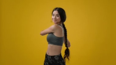 Güçlü, zayıf, seksi Hintli, etnik kadın sporcu, bayan sporcu, bayan sporcu, sarı stüdyo arka plan egzersizi, el egzersizi, boyun bükme, yoga, vücut geliştirme, gerdirme.