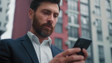 Erkek işadamı cep telefonuyla mesajlaşırken çevrimiçi arama bilgileri okurken 30 'lu yaşlardaki Kafkasyalı serbest çalışan modern akıllı telefon internet medyası Wi-Fi kullanıyor.
