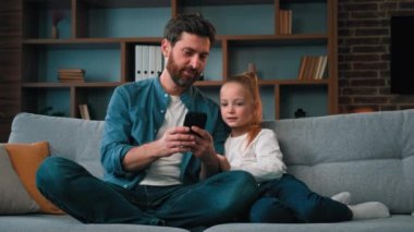 Mutlu aile kızı ve bekar baba modern aletlere bakın akıllı telefon videoları online internet iletişim kafkasyalı baba kızına cep telefonu ebeveyn kontrolünü kullanmayı öğretiyor.
