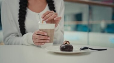 Bilinmeyen müşteri müşterisi kız öğrenci kafe restoranında oturur latte kahvesinde şeker karıştırır sıcak kafein içeceği espresso kapuçino içer lezzetli çikolatalı pasta yer tatlı, besleyici tatlı yer.