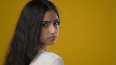 Sarı stüdyodaki portre üzgün, Hintli kadın endişeli, endişeli, bunalımlı, depresyondaki, umutsuzluğa kapılmış, umutsuzluğa kapılmış, kameraya bakan umutsuz model sorunu yüzünden acı çekiyor.