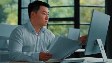Profesyonel Asyalı iş adamı Koreli 40 'lı yaşlardaki Japon avukat ofis çalışanı finansal belgeleri okuyor fatura sözleşmesi bütçe belgelerini araştırıyor iş verilerini internetteki bilgisayar ödeme faturalarında arıyor