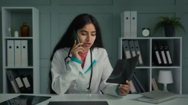 Genç Arap doktor kadın pratisyen doktor cep telefonu danışmanlığı yapan bir hasta, röntgen iskelet tomografisi sonucuna uzaktan bakıyor.